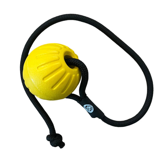 A yellow textured dog toy ball with a black rope attached.