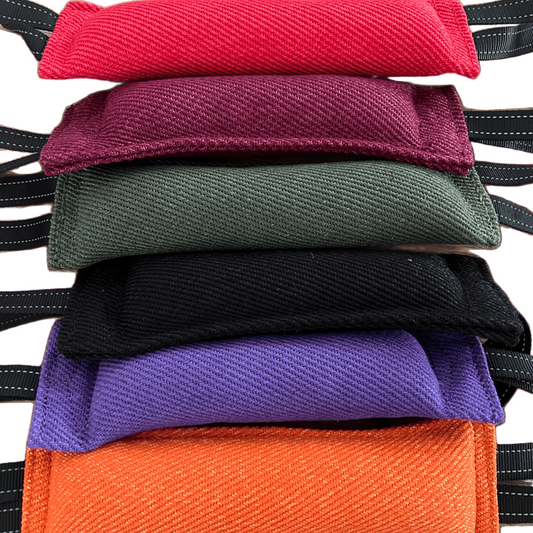 Sixdog tug toys in different colors (red, burgundy, olive green, black, purple, and orange) with black stitched straps, shown against a solid white background.